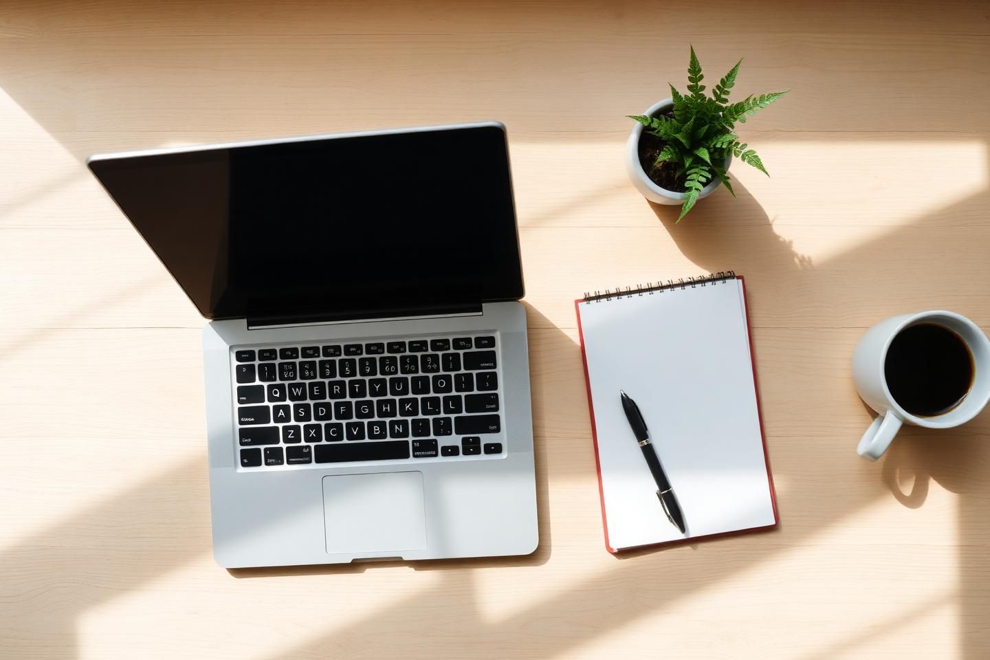 Skrivbord med laptop som visar RegisterDatas produkter och adressregister, anteckningsblock och kaffe i morgonsol